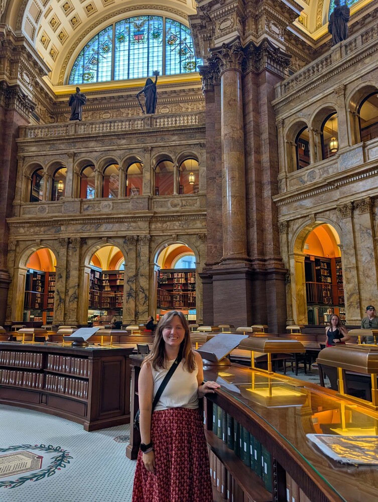 woman smiling standing in a library with marble pillars