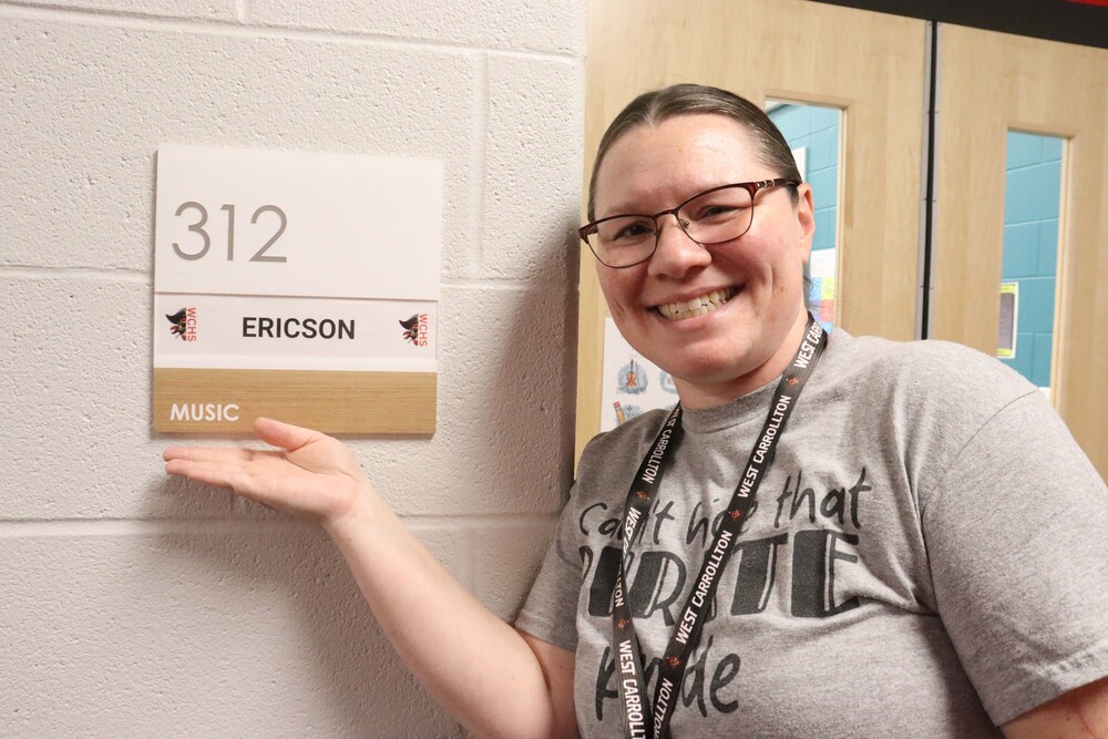woman smiling in hallway with her hand under a sign that says 312 Ericon Music