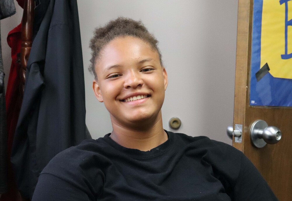 Girl smiling wearing a black tshirt with her hair pulled back