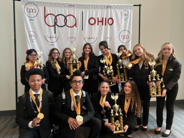 girls and boys wearing medals with five holding trophies