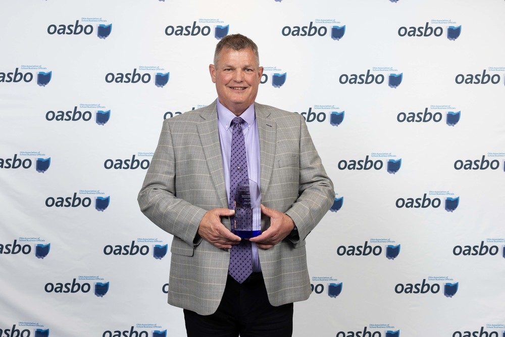 Man in suit holds an award