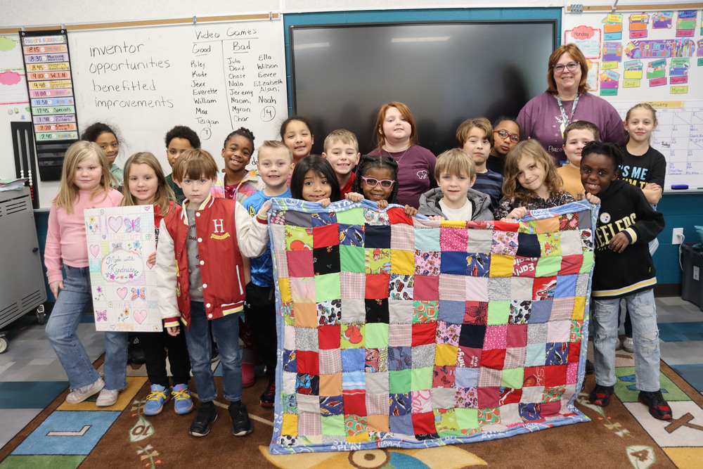 group of students holding a blanket