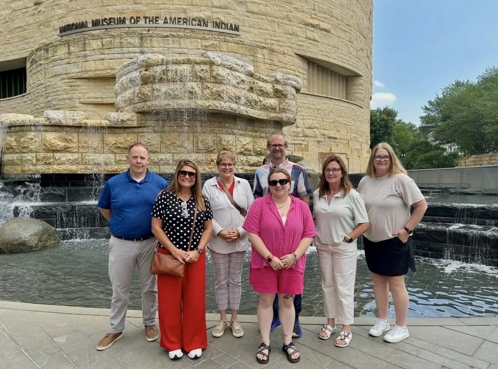 Group of people pose in front of the National Museum of the American Indian