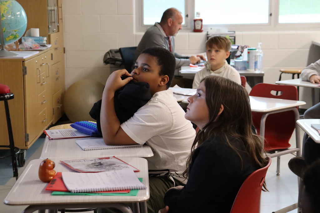 3 students with teacher in the background during fire prevention presentation