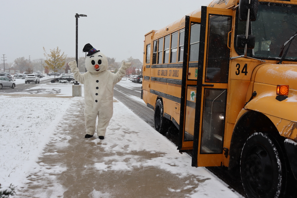 person in snowman costume standing beside a bus