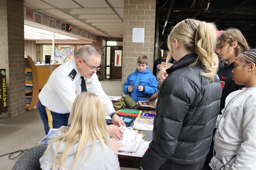 students gathered around a table with pictures and items from the military
