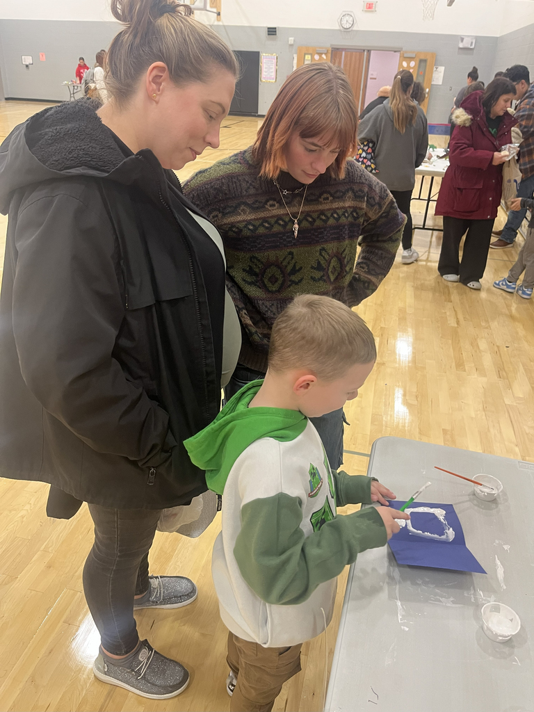 child doing an activity at STEAM Night while being watched by two adults