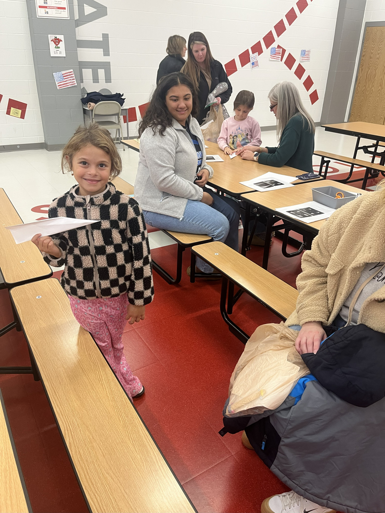 girl holding a paper airplane with adults in the background