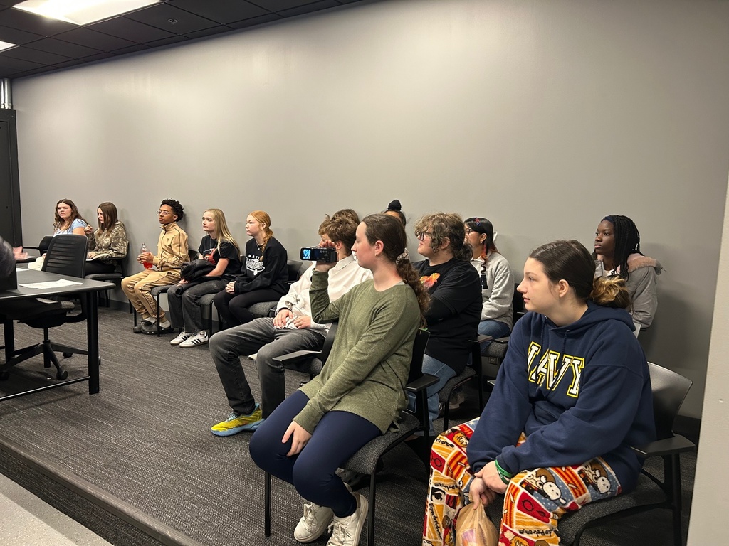 students in a presentation with one recording with a video camera