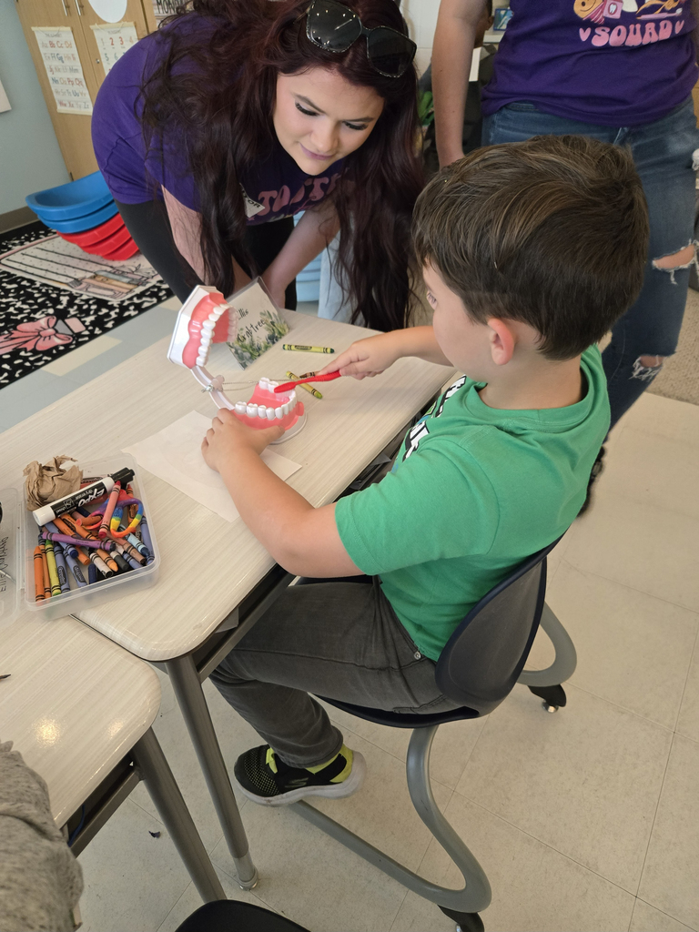 student brushing teeth in a mouth model