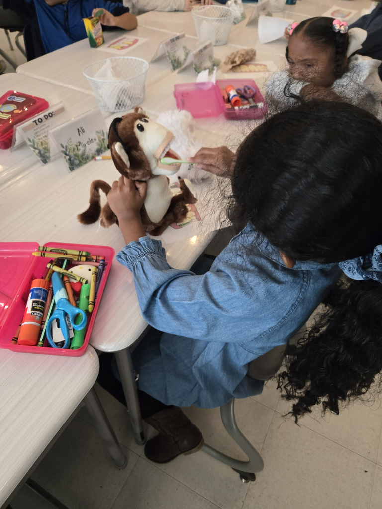 girl brushing teeth of a stuffed animal