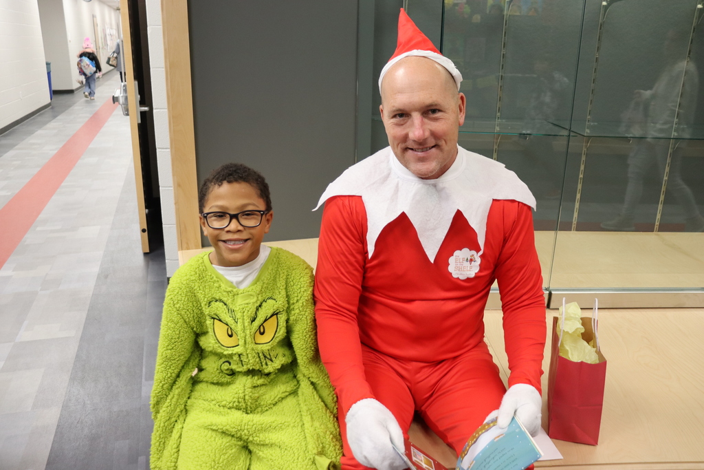 elf sitting with a child in a grinch outfit