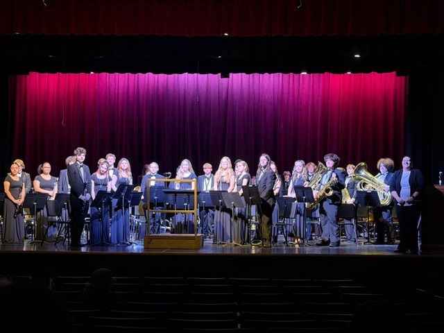 High School Winds Instrument musicians on stage with band director 