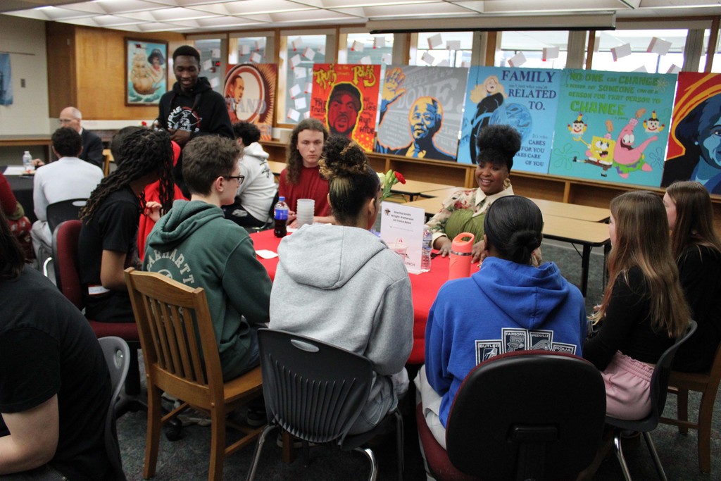 Students in a small group at a table meeting with a business partner