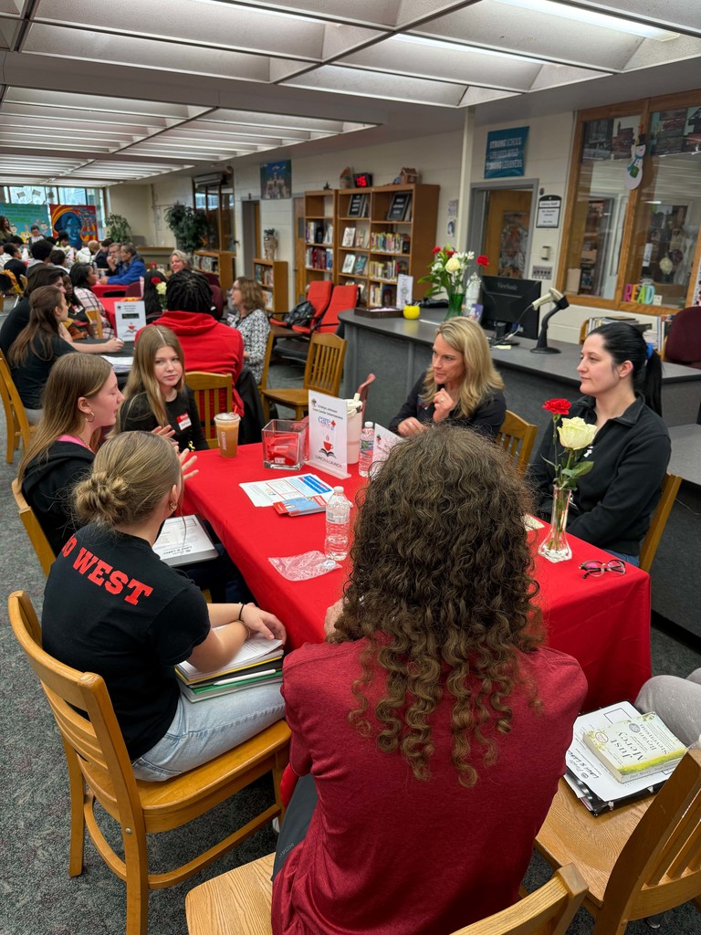 Students in a small group at a table meeting with a business partner