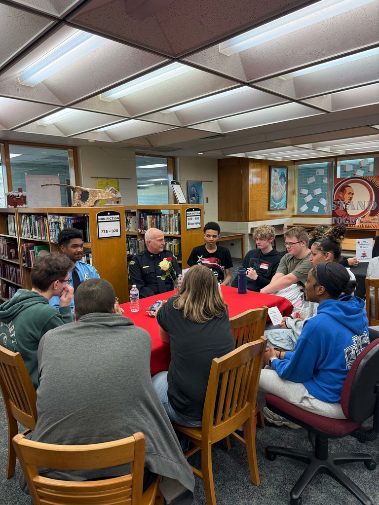 Students in a small group at a table meeting with a business partner