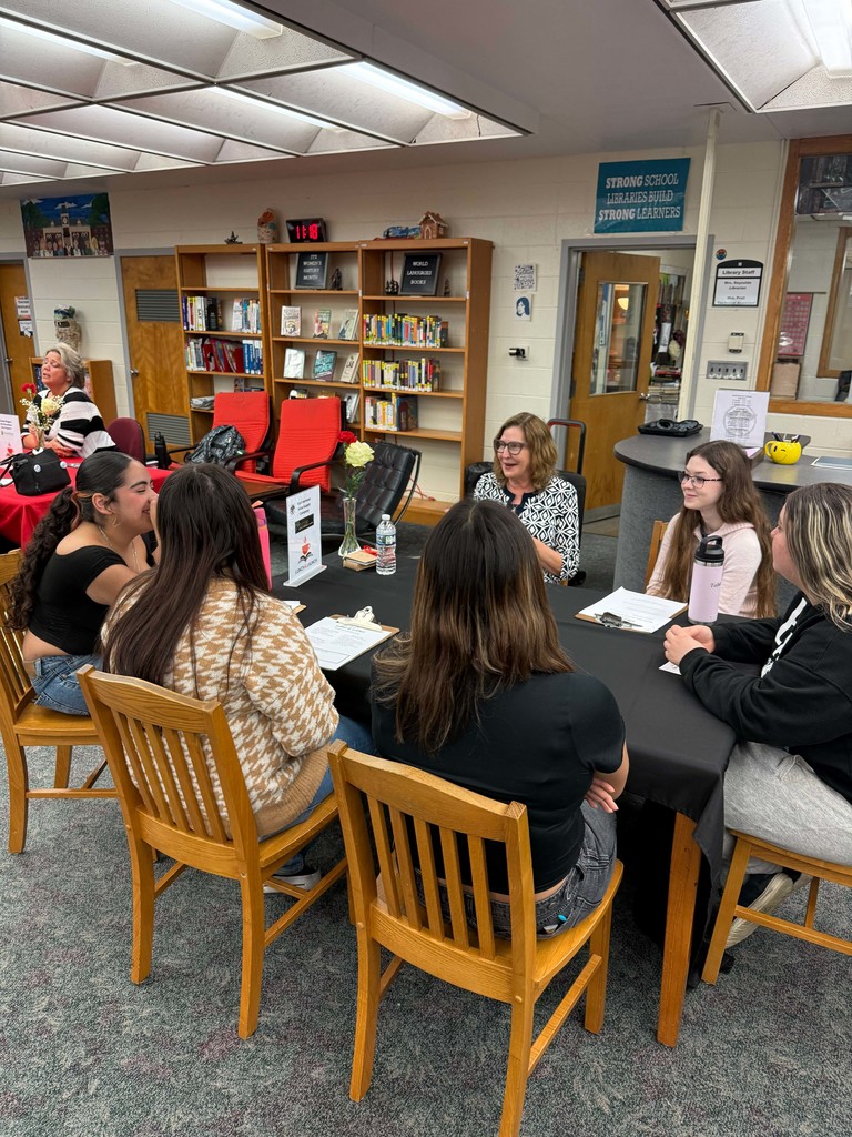 Students in a small group at a table meeting with a business partner