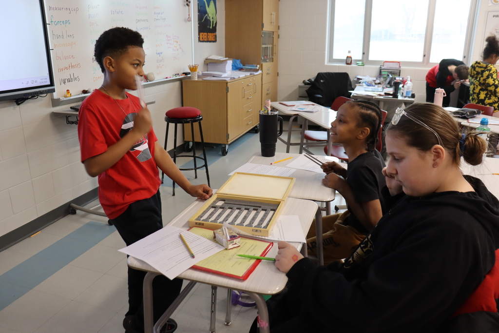 three students listening to tuning forks in a science experiment