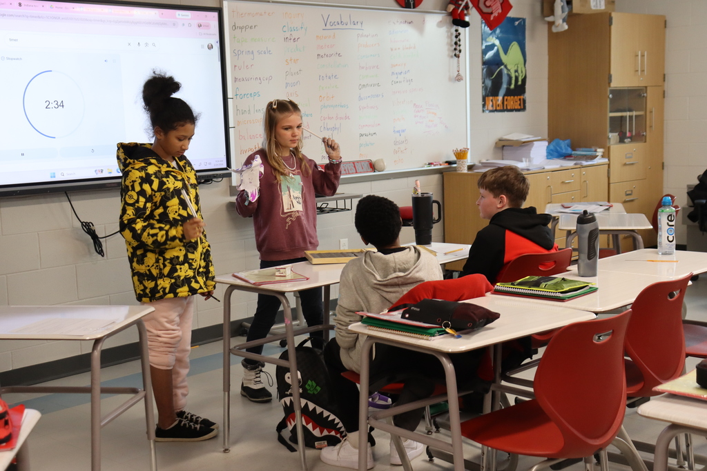 four students listening to tuning forks in a science experiment
