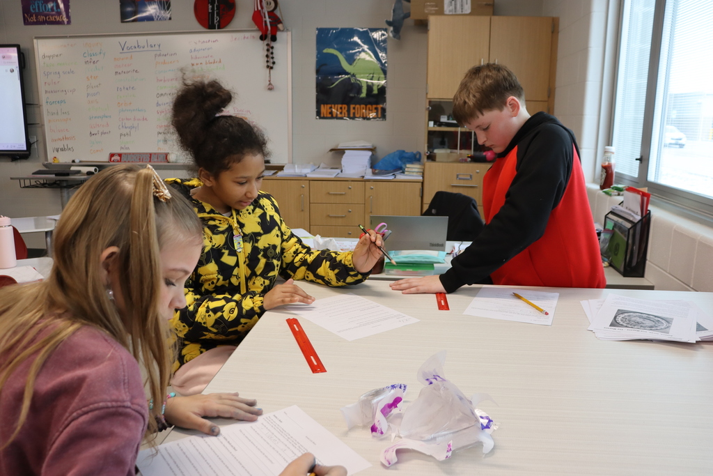 three students making sounds with rulers  in a science experiment