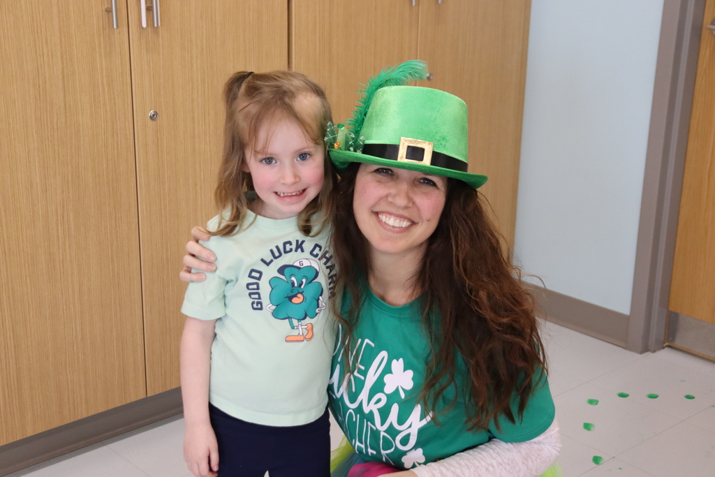 girl with green tshirt with her teacher who is wearing a green hat and green tshirt