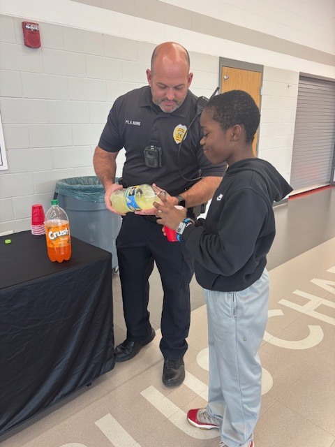 Police officer pouring soda for a student