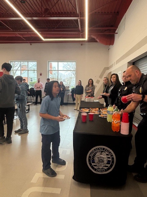 A child holding pizza on a plate waits for a soda