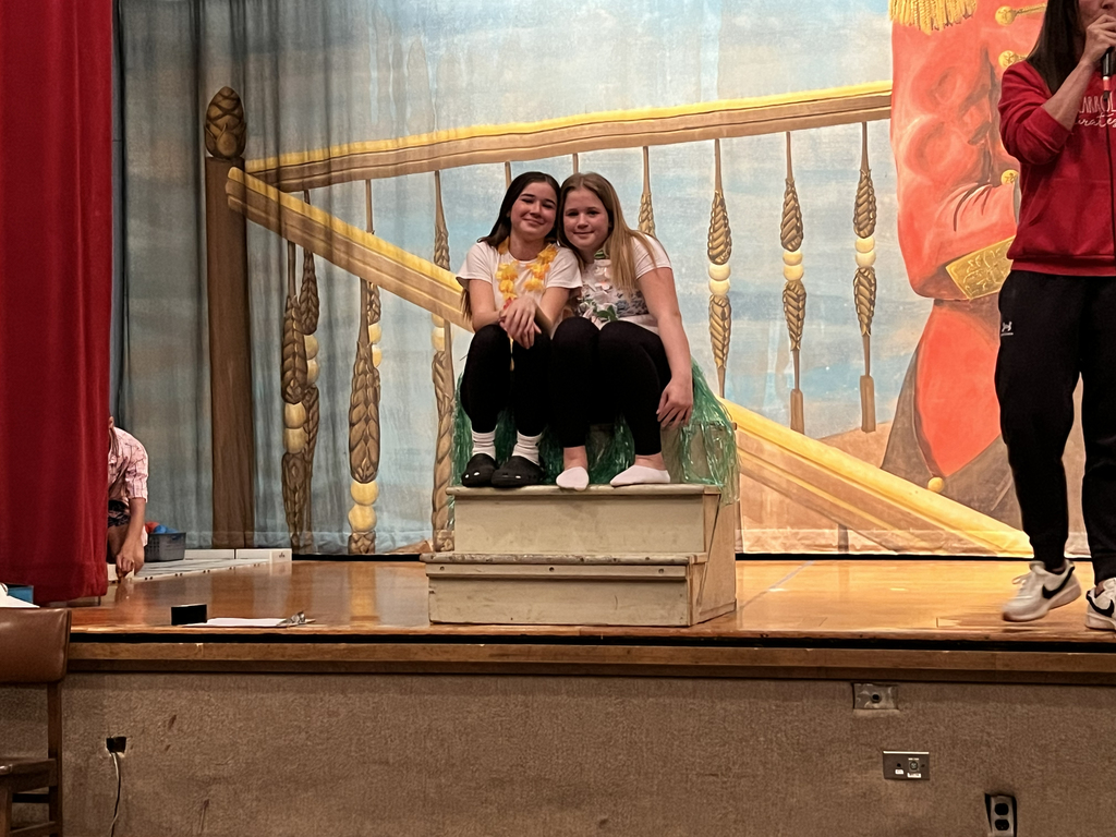 two girls sitting together on stage