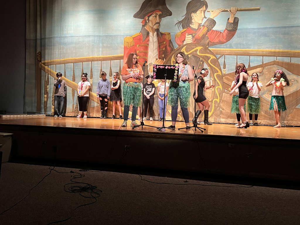 2 teachers on stage with students behind them