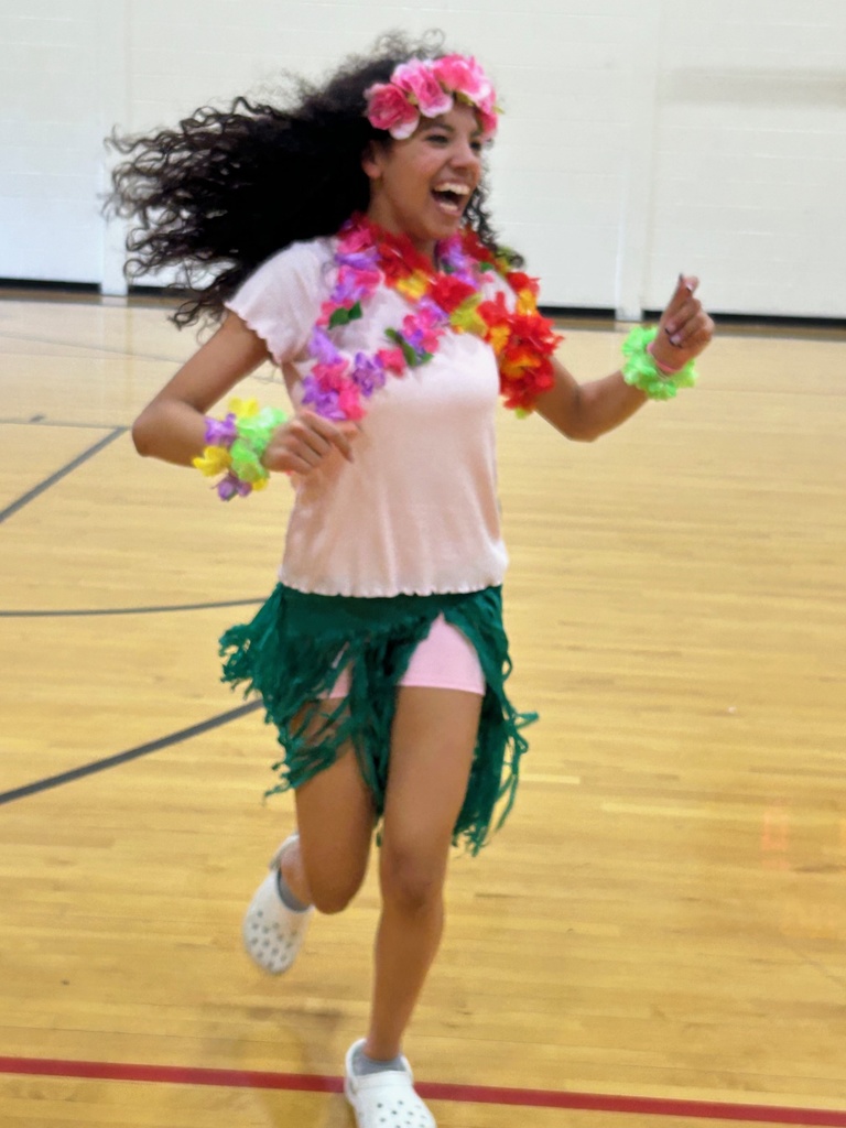 Girl with flowers in her hair and a hula skirt running and laughing