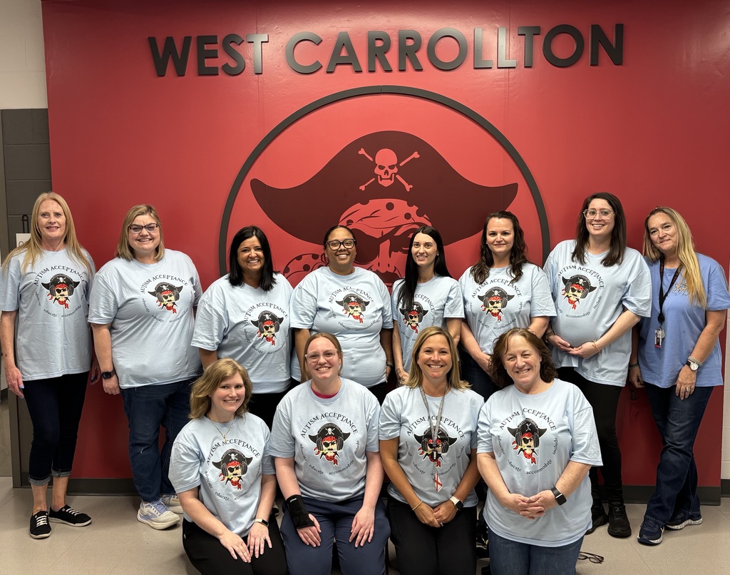 A group of women in matching shirts pose for a photo in front of a red wall.