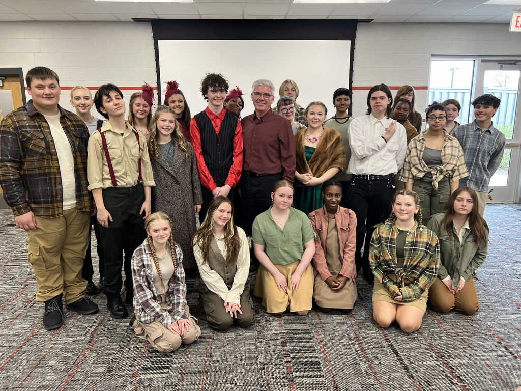 A group of individuals dressed in costumes posing for a photo in a room.