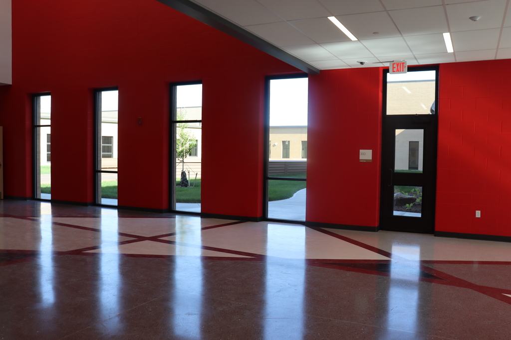 An empty room with red walls, white trim, and glass windows. A red and white design on the floor.
