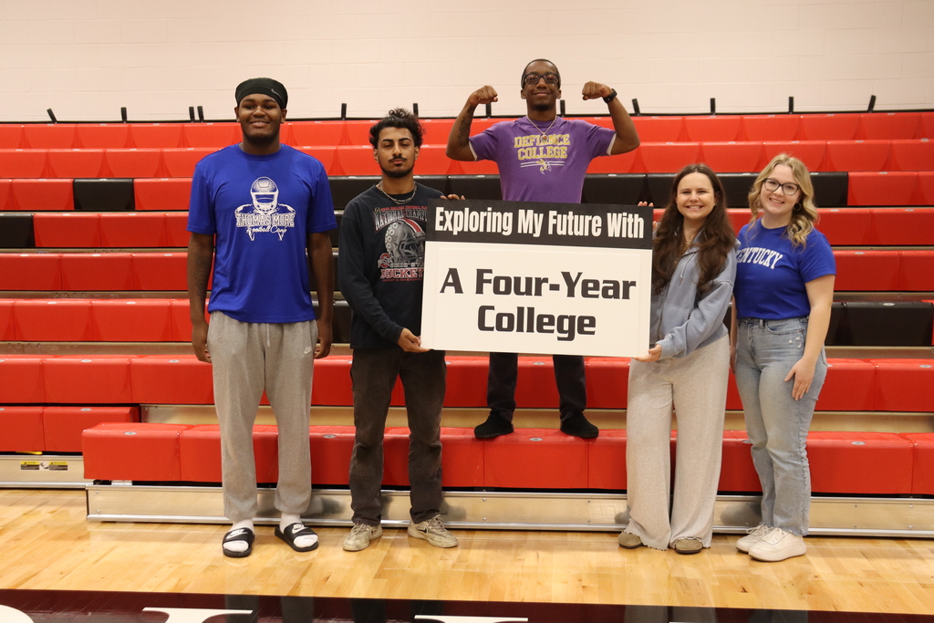 Five individuals with red bleacher behind them holding a sign that says "Exploring My Future With a Four-Year  College"