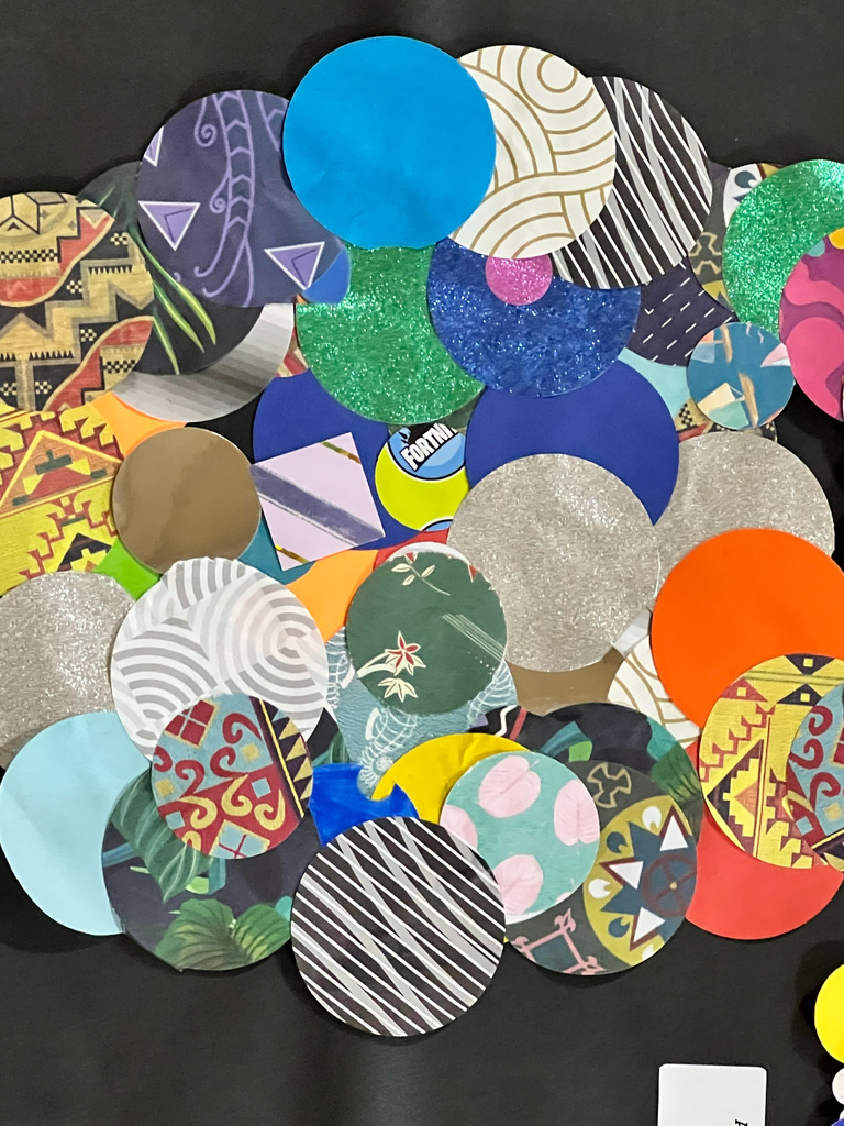 A collection of circular papers with various patterns and colors arranged on a black background.