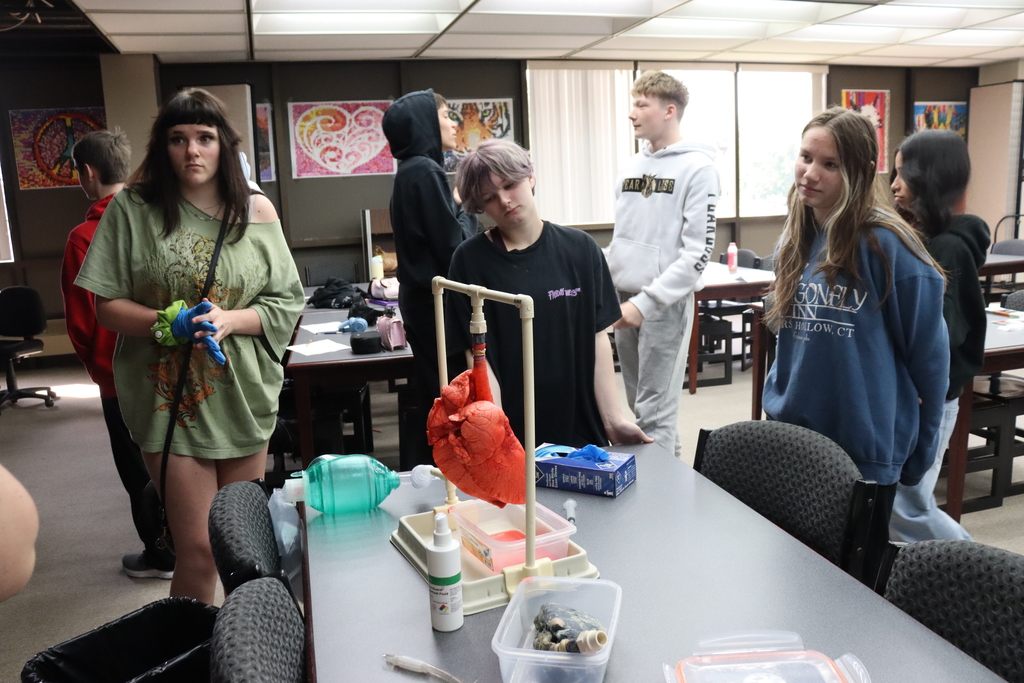 Multiple people in a room, with one person in front of a table displaying a life-size model.