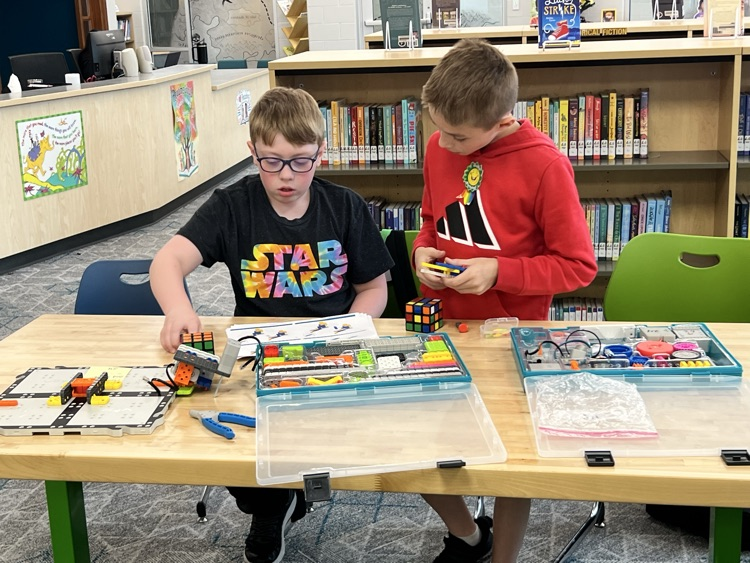 boys working together using colorful pieces to construct a robotic arm
