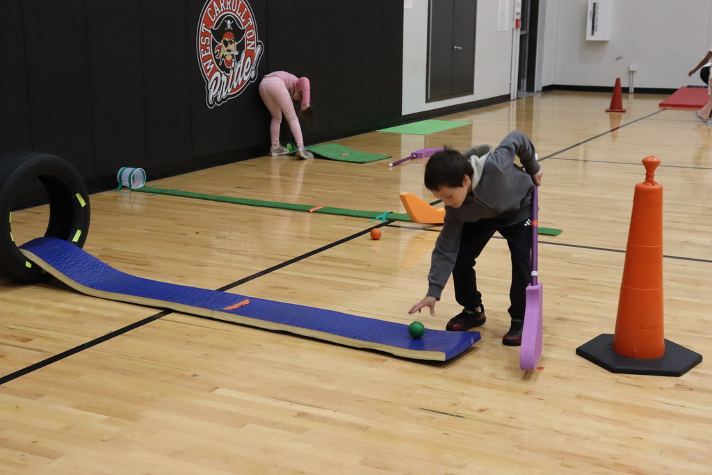 A child aims and throws a ball at a target. Another child picks up a ball behind him.