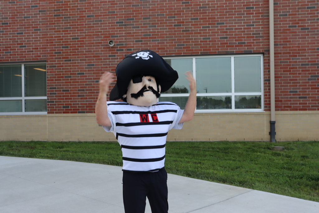 A person dressed as a pirate mascot in front of a red brick building.