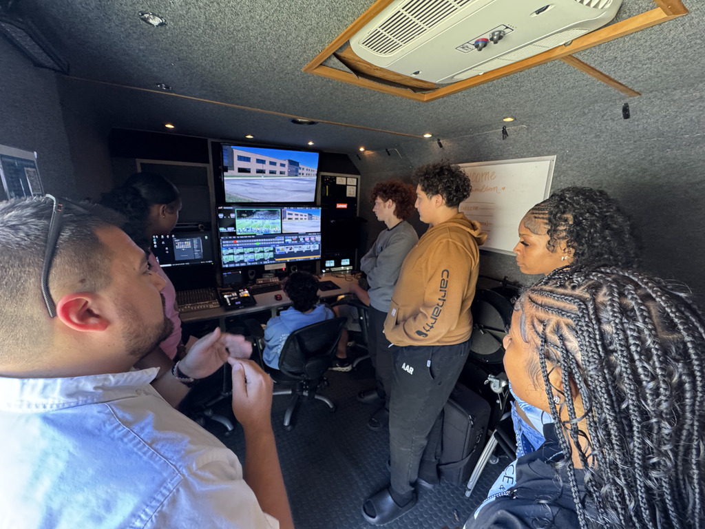 Several individuals in a room with monitors and equipment. 