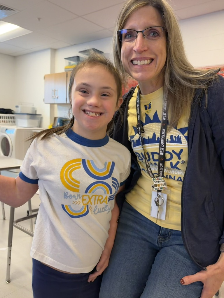 A woman in a yellow shirt and glasses stands with a smiling child in a white shirt.