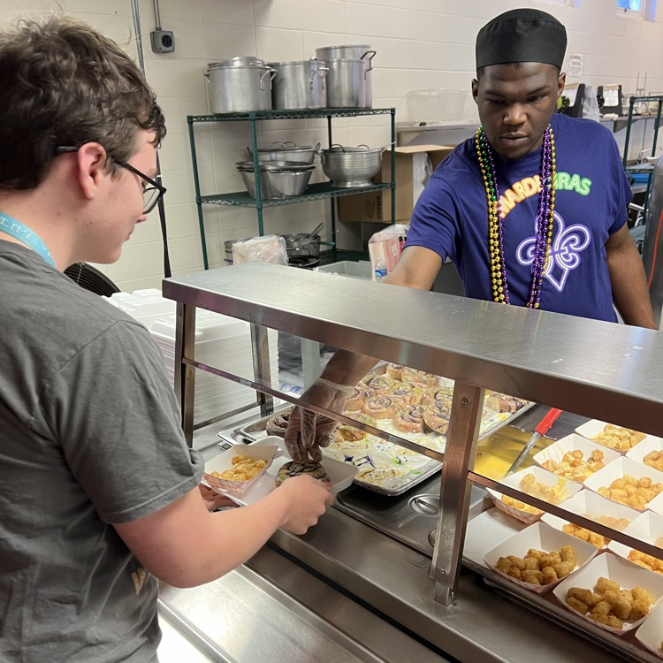 cafeteria staff member hands out king cake