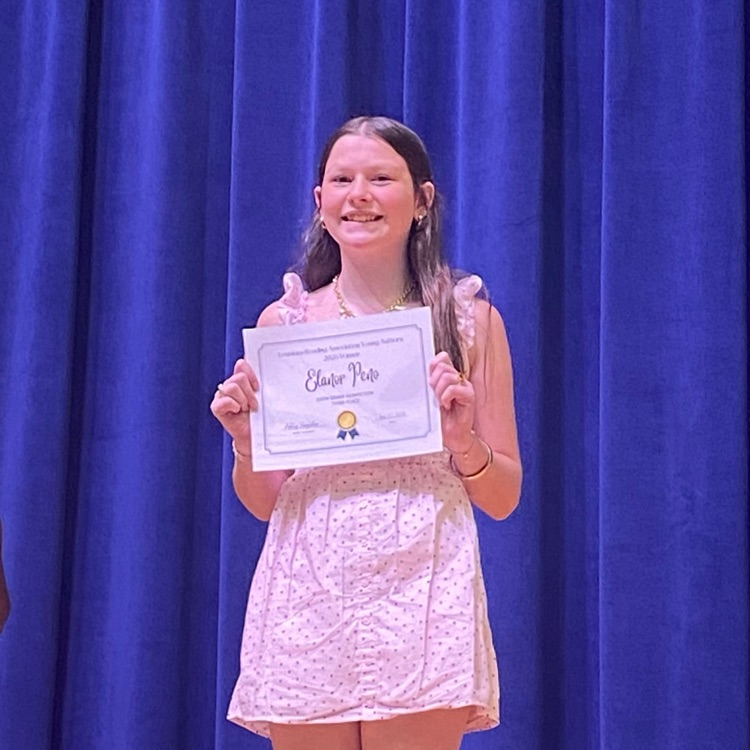 Student stands on stage with certificate 