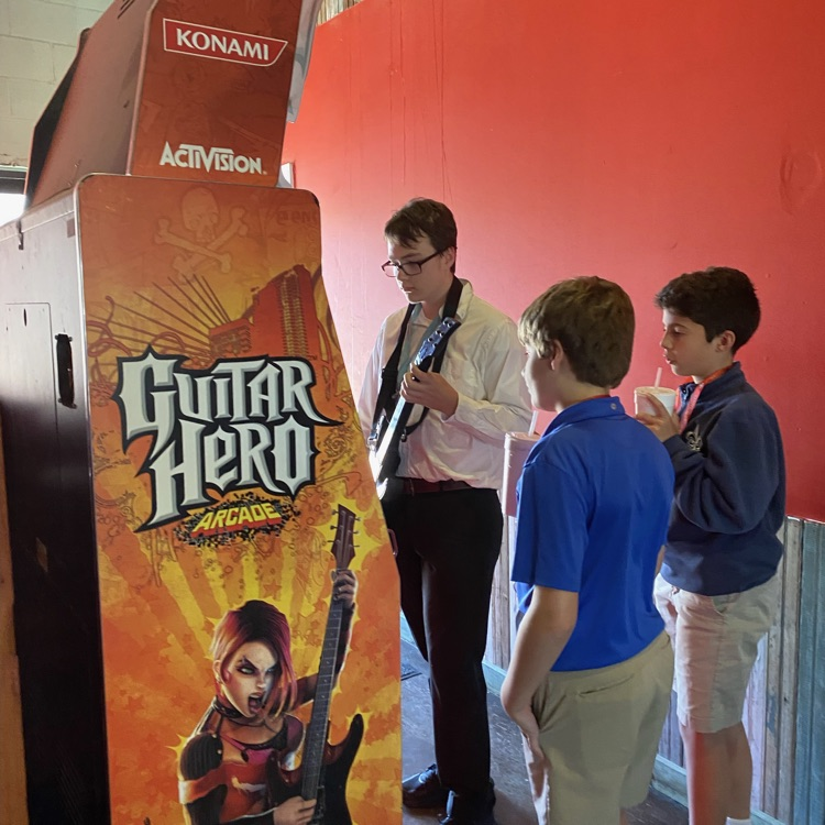 student plays video game as friends watch