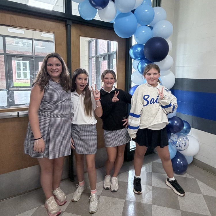 students pose in front of a balloon arch