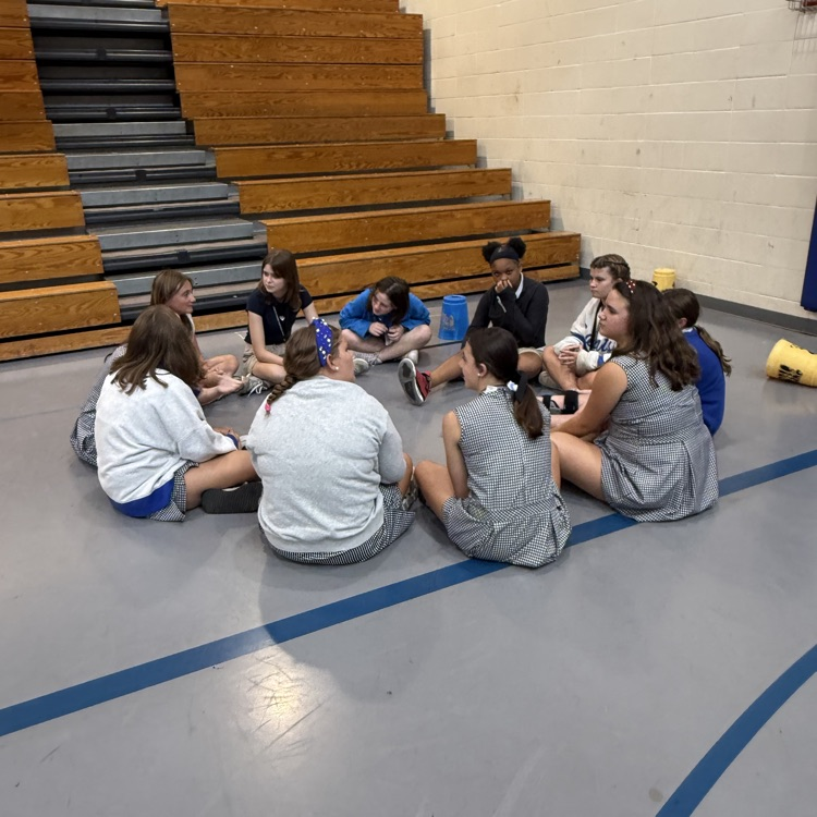 girls sit in a circle in the gym