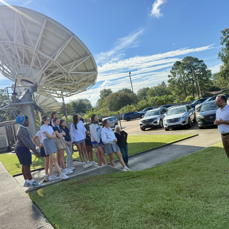 students pictured in front of large satellite receiver