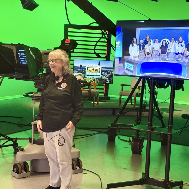 woman picture on set with students appearing on screen behind her