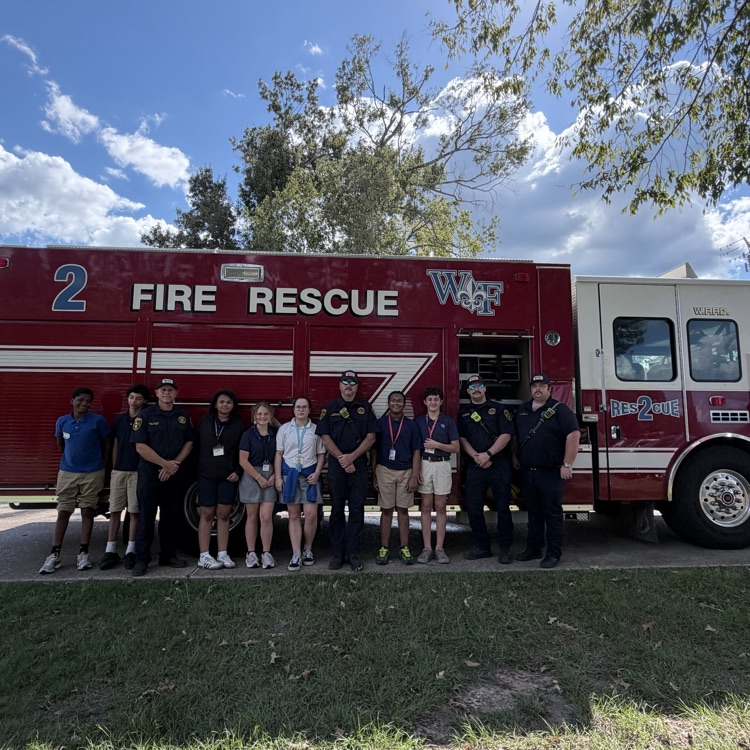 students stand in front of fire truck with firemen