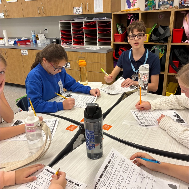 middle school student works with elementary students